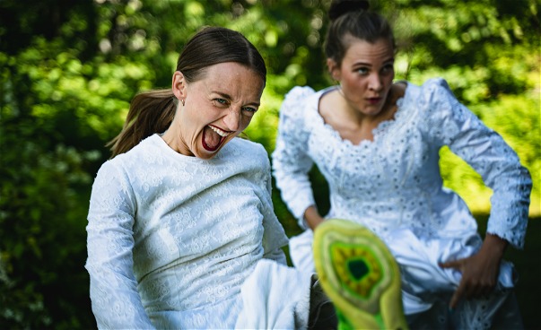 Två dansare springer utomhus i bröllopsklänningar och gymnastikskor
