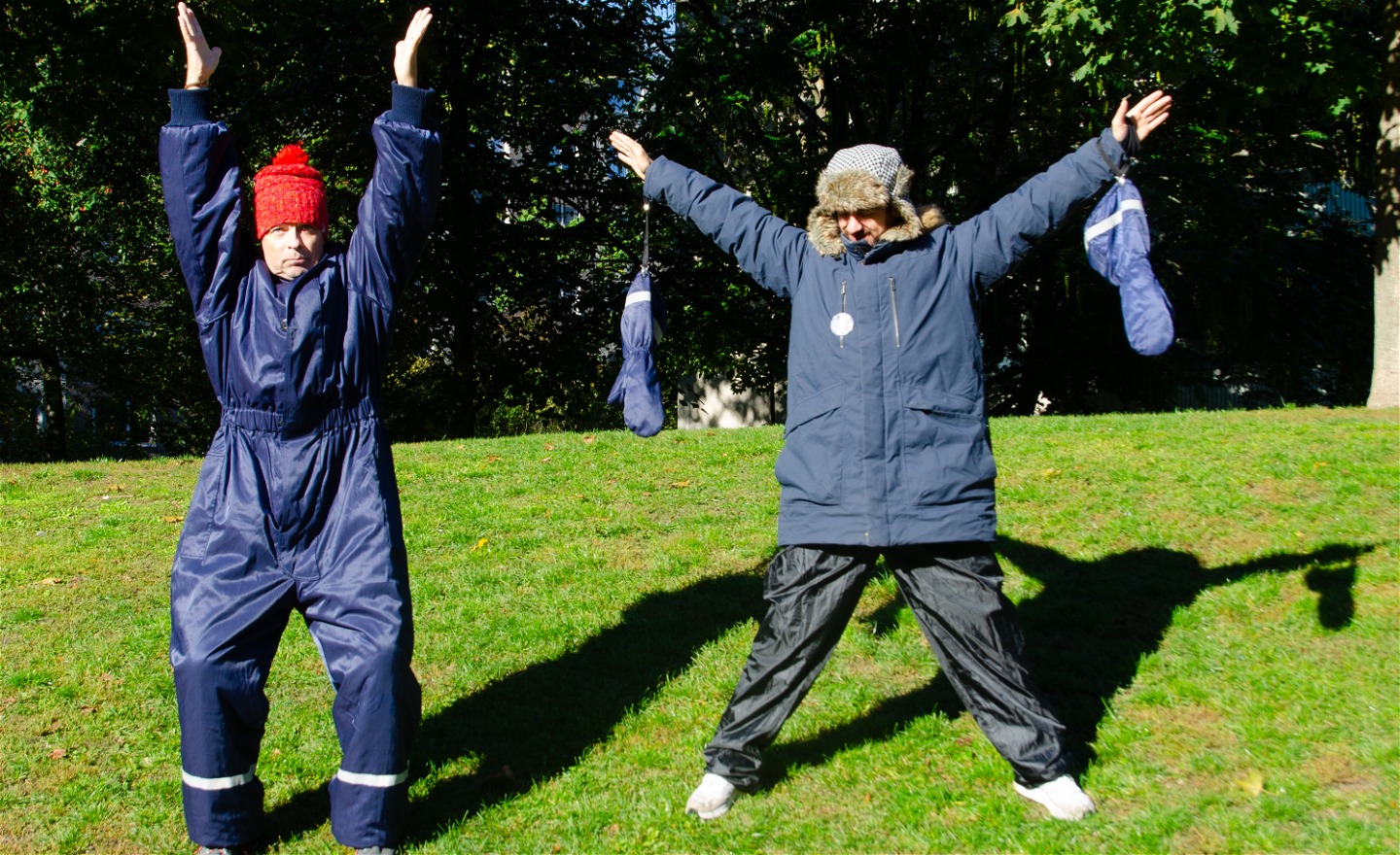 Två vinterklädda figurer står med armarna upp åt olikah¨ll.