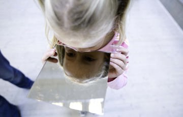En flicka tittar ner i en spegel.