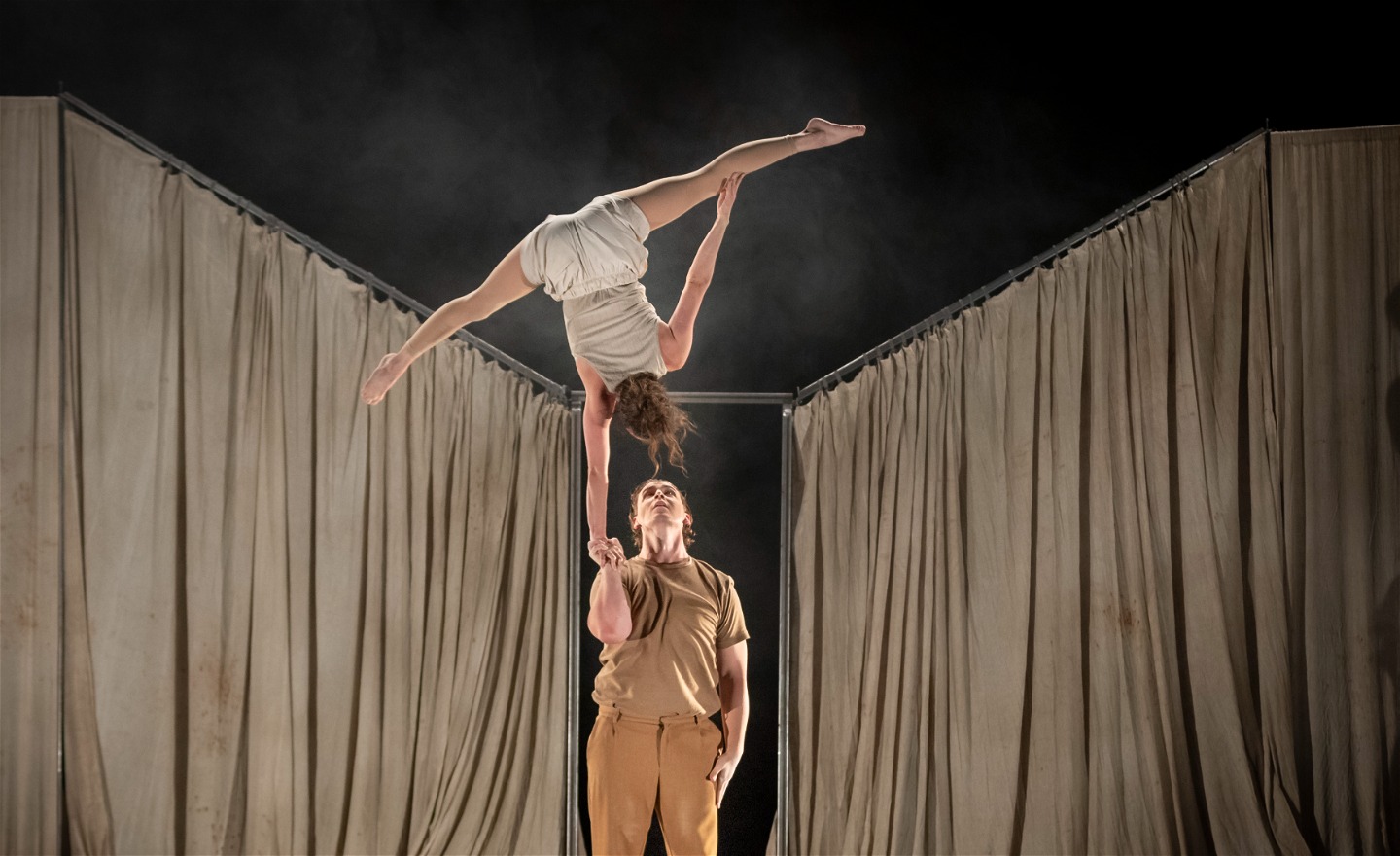 Foto från föreställningen PACE. Axel balanserar Sara i sin hand. Sara står upp och ner på en hand.