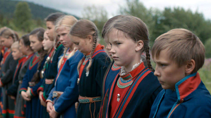 Barn på rad bredvid varandra klädda i samiska kläder.