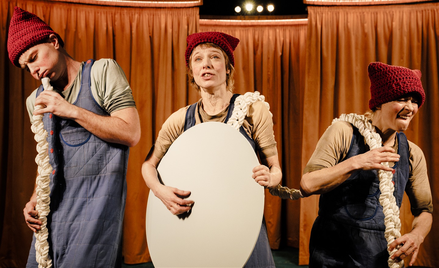 Tre personer med likadana kläder har skapat en liten orkester av ett rep, en sjunger, en spelar gitarr och en spelar ståbas.