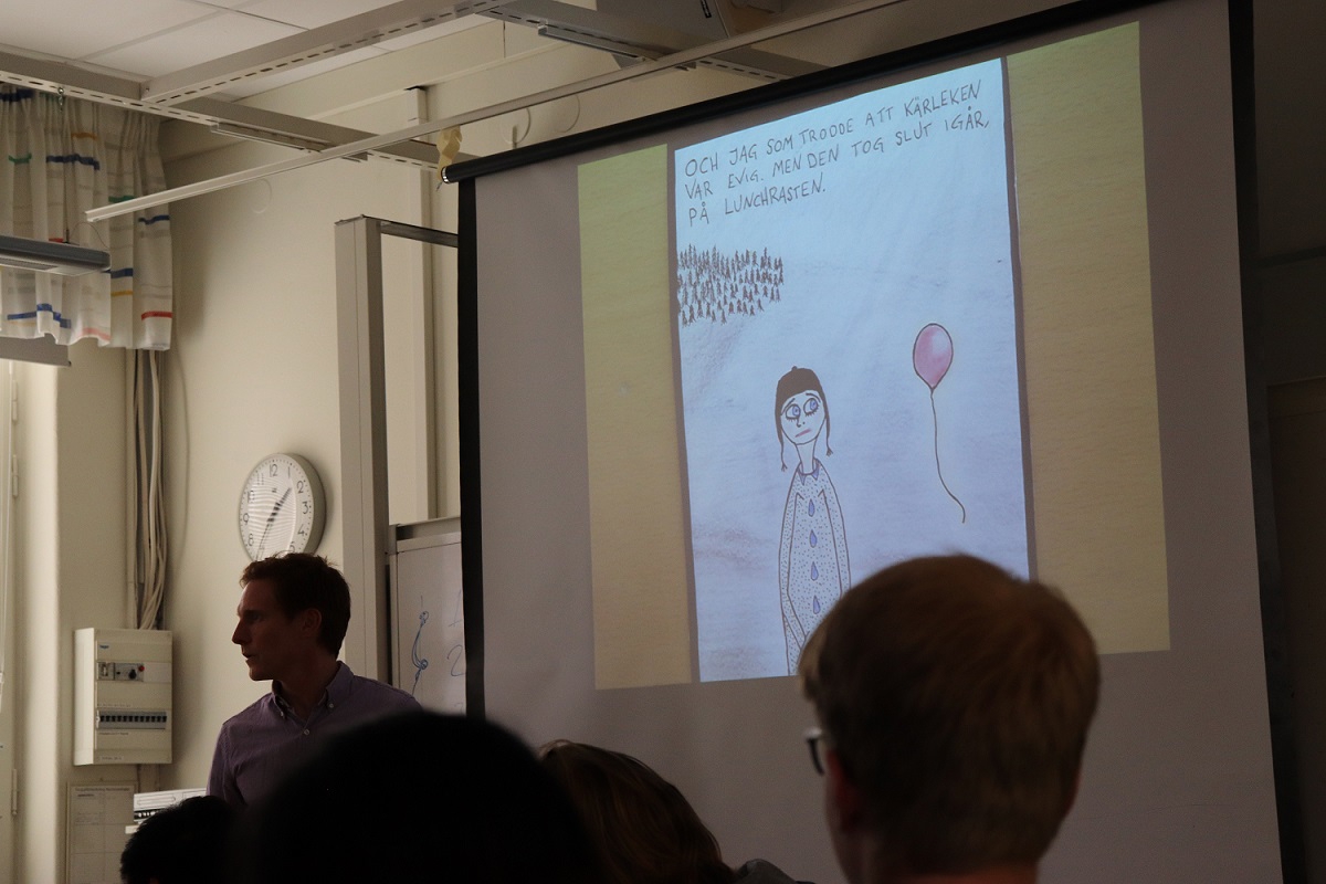 ett nedsläckt klassrum med en smartboard som visar en teckning av en människa och en ballong.