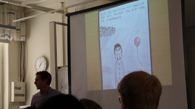 Ett nedsläckt klassrum med en smartboard som visar en teckning av en människa och en ballong.