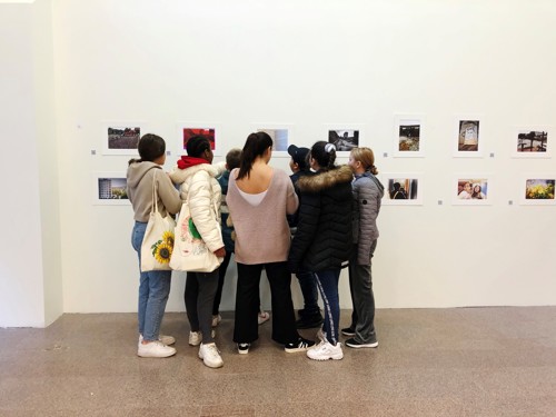 Foto, elever står och tittar på varandras foton