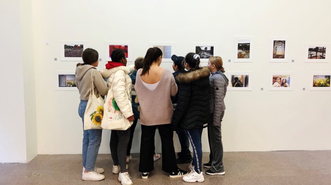 Elever tittar på fotografier på en vägg i en utställningslokal.