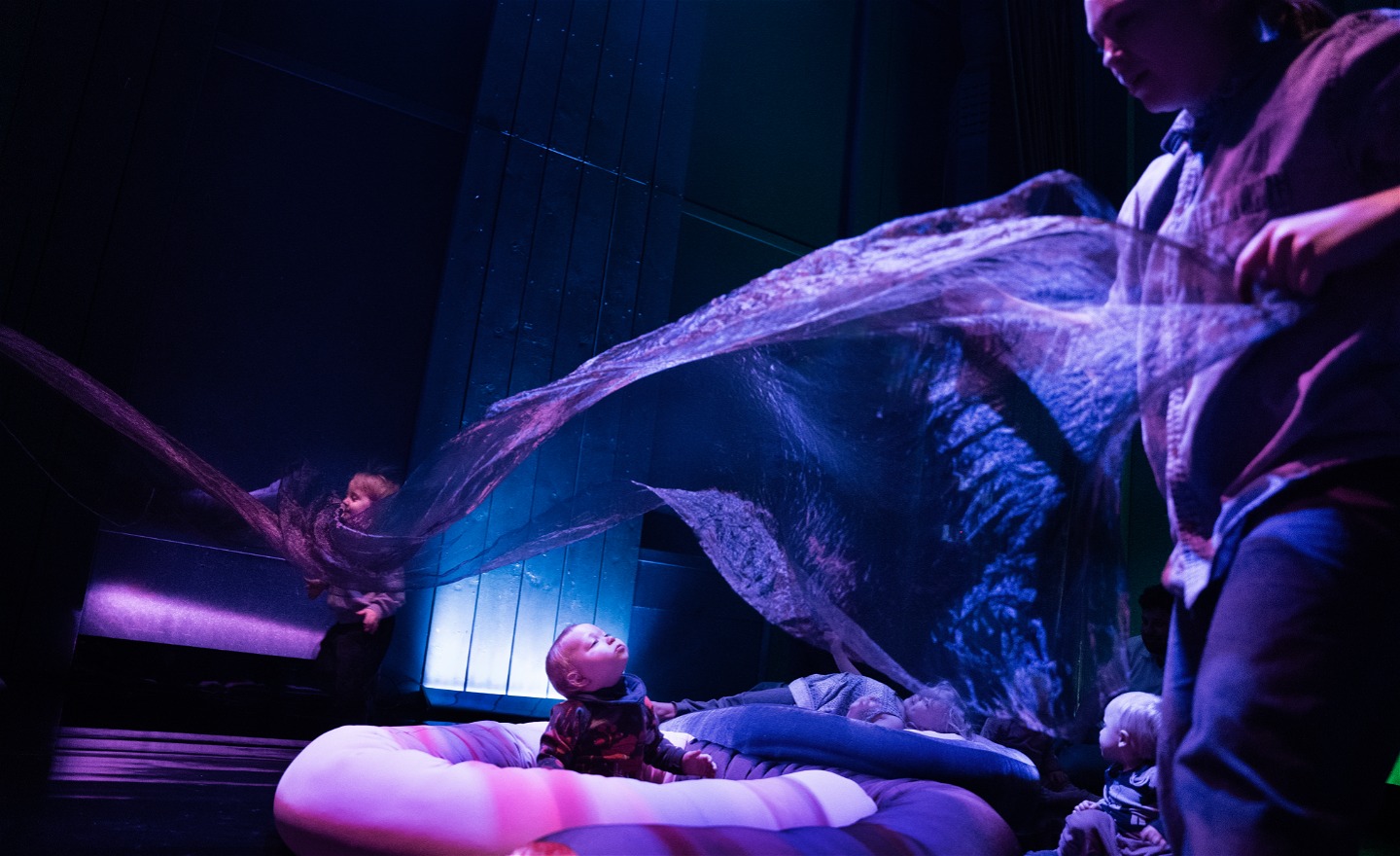 Ett barn tittar upp mot ett böljande tunt tyg