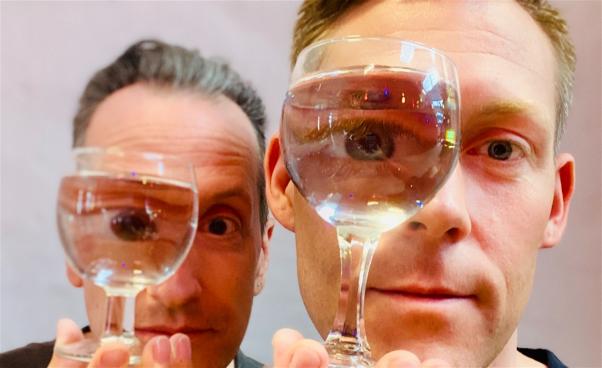 Två män tittar genom vattenfyllda glas.