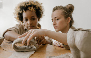 Två personer skapar föremål i lera.