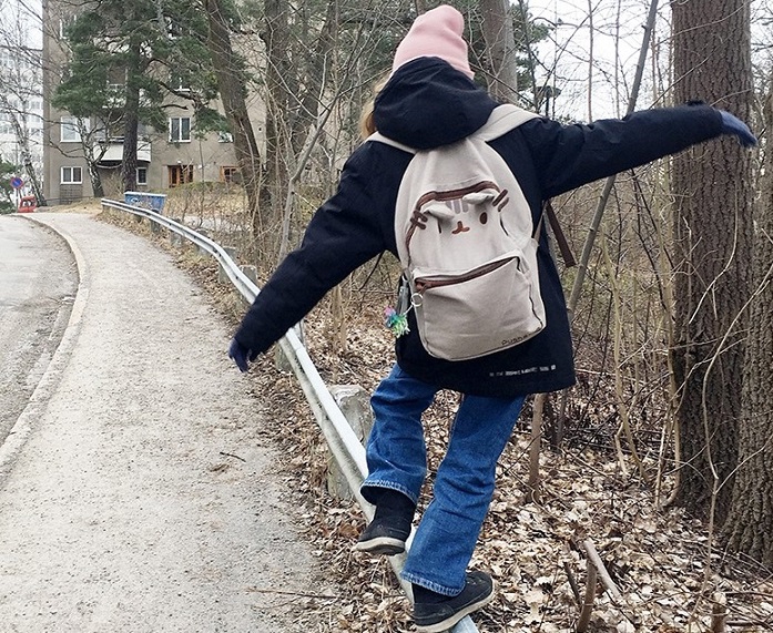 ett barn balanserar på ett vägräcke.