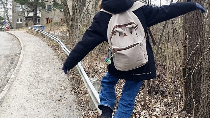 Ett barn balanserar på ett vägräcke.