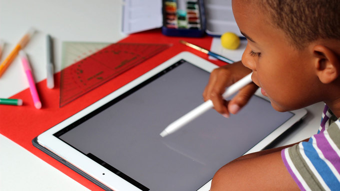 Ett barn ritar på en Ipad.
